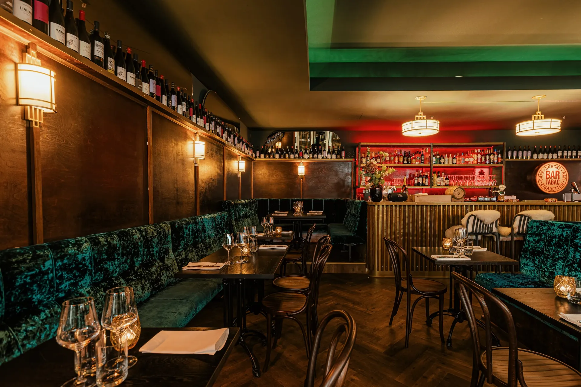 Gastraum der Bar Tabac mit grünen Samtbänken und warmem Licht.