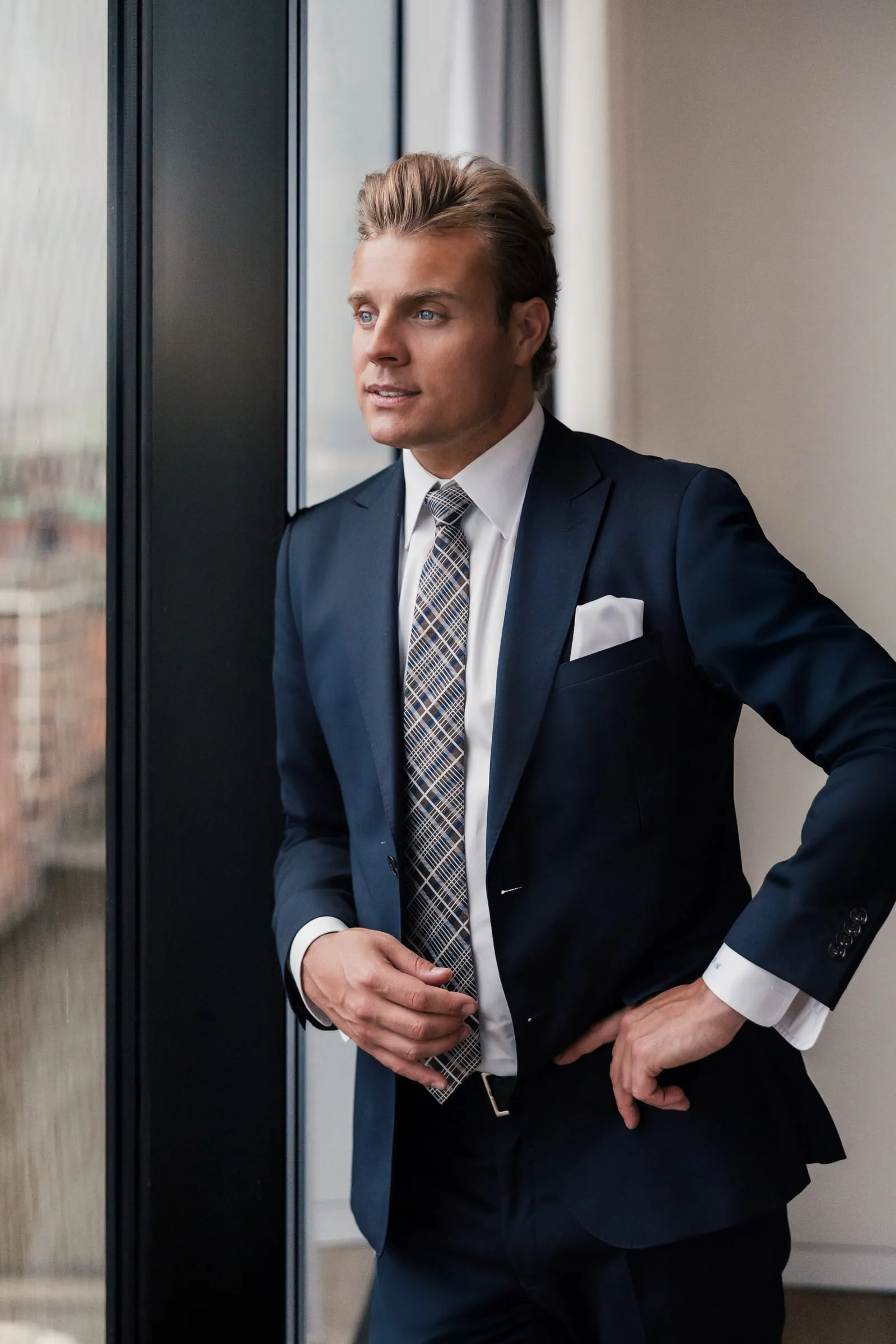 Björn Meins im dunkelblauen Anzug am Fenster, Blick nach draußen.