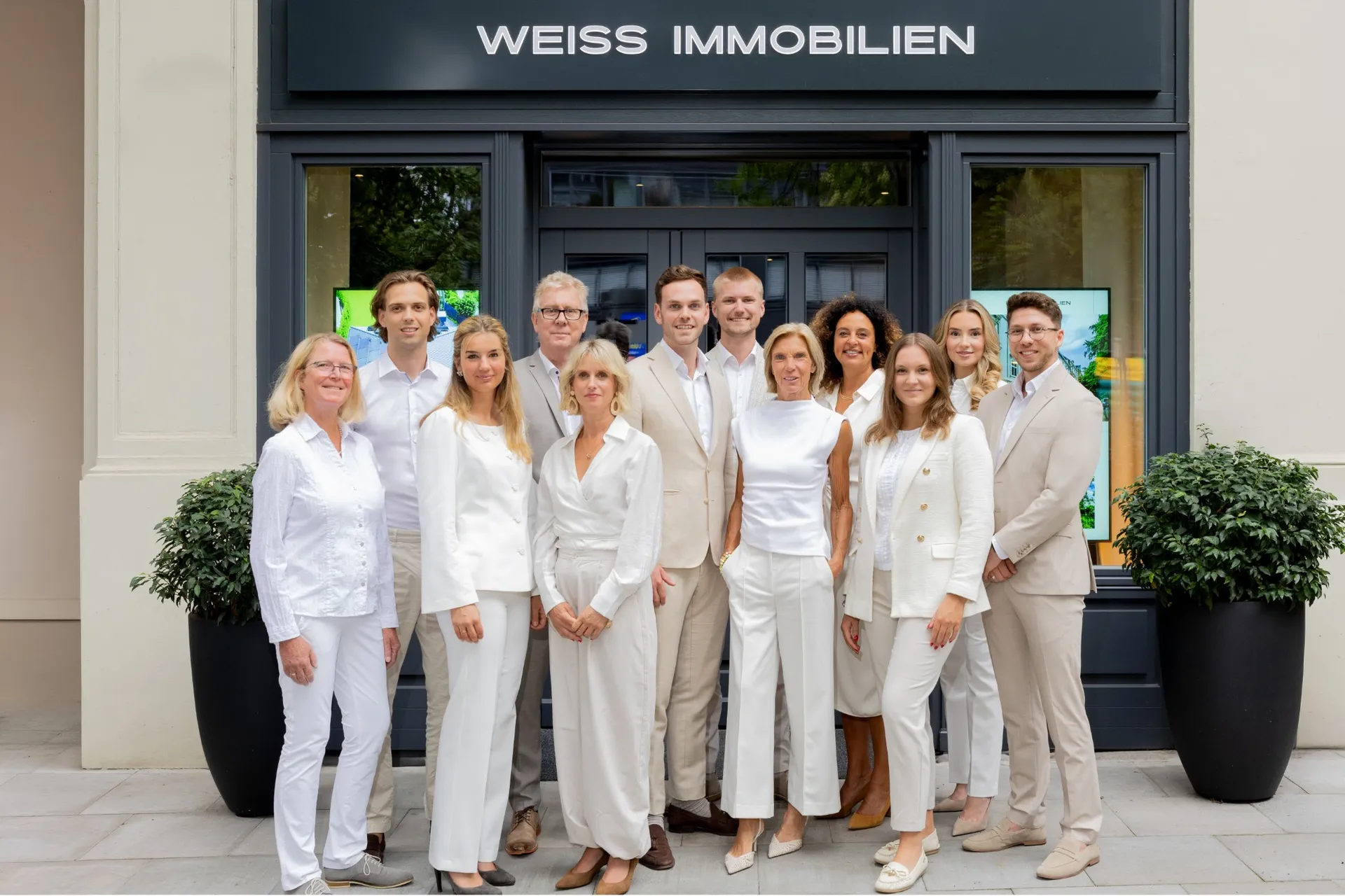 Das Team von Weiss Immobilien vor dem Geschäft mit Schriftzug.